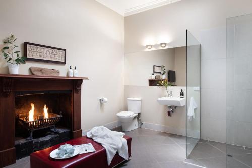 a bathroom with a fireplace and a toilet and a sink at Maple - quaint cottage with fireplace and spa in Daylesford