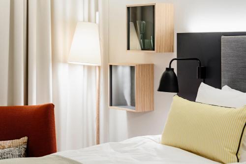 a bedroom with a bed with a lamp and a chair at Hotel Indigo Helsinki-Boulevard, an IHG Hotel in Helsinki