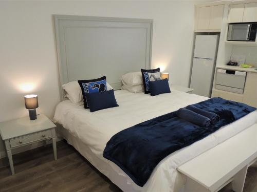 ein Schlafzimmer mit einem großen weißen Bett mit blauen Kissen in der Unterkunft Studio 37 @ The Dunes in Plettenberg Bay