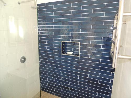 eine blau geflieste Dusche mit einer blau gefliesten Wand in der Unterkunft Studio 37 @ The Dunes in Plettenberg Bay