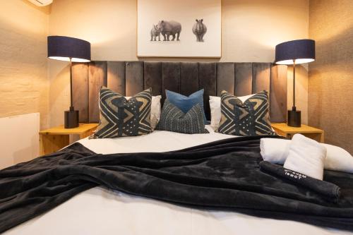 a bed with a black blanket and pillows on it at Fever Tree Guesthouse in Hillcrest