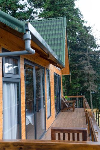 a house with a wooden deck with a porch at Sapa Pine Hill Eco Lodge in Sa Pa