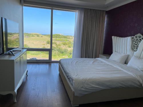 ein Schlafzimmer mit einem großen Bett und einem großen Fenster in der Unterkunft Ocean Star Resorts - Seopjikoji in Seogwipo