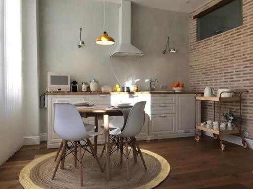 cocina con mesa de madera y sillas blancas en Lloēco - Art & Design Guest House, en León