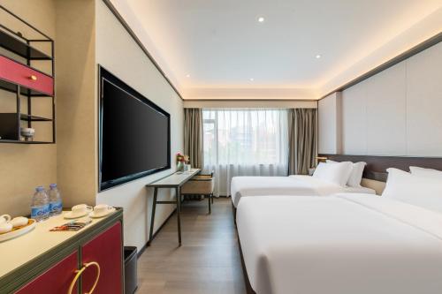 a hotel room with two beds and a flat screen tv at Fushang Hotel (Railway Station Yuexiu Park Sun Yatsen Memorial Hall Branch) in Guangzhou