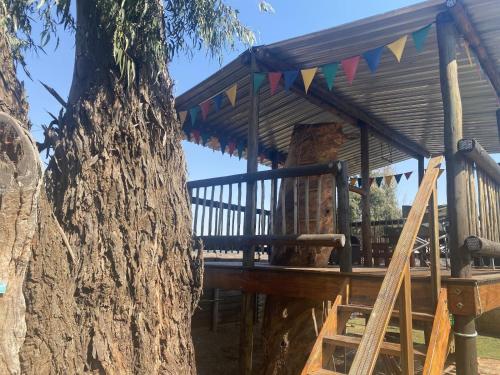 a wooden tree house with flags on it next to a tree at Eastwoods Lodge in Springs