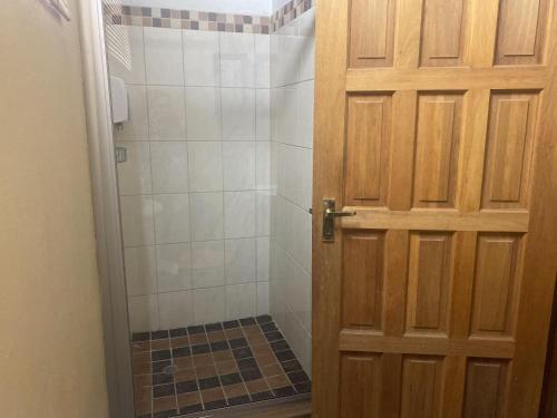 baño con ducha y puerta de madera en Eastwoods Lodge, en Springs