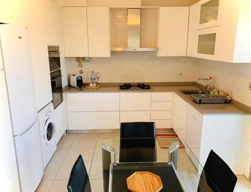 uma cozinha com armários brancos e uma mesa e cadeiras em Apartamento ALTAMIRA T2 SERRA SHOPPING na Covilhã