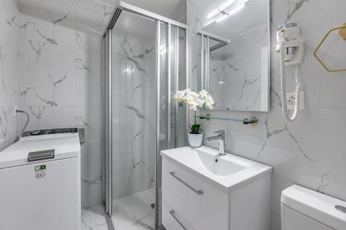 a white bathroom with a sink and a shower at Garden of Eden 1-bedroom apartment – Lakefront in Territet