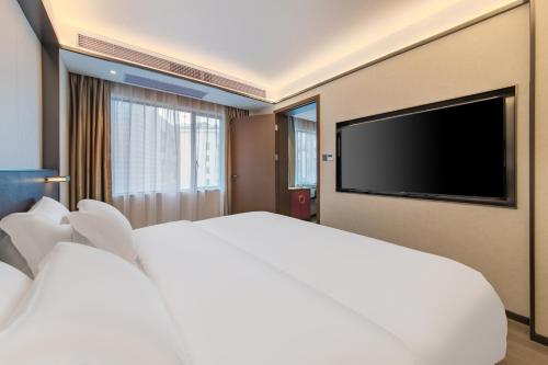 a bedroom with a large bed and a flat screen tv at Fushang Hotel (Railway Station Yuexiu Park Sun Yatsen Memorial Hall Branch) in Guangzhou