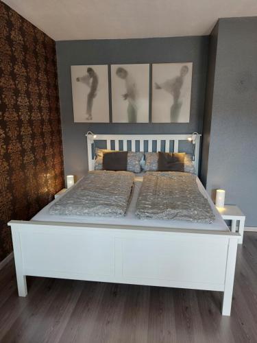 un letto bianco in una camera da letto con tre immagini sul muro di Apartment 358 mit Sauna, Schwimmbad und Fitness a Schönwald