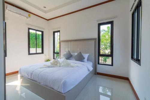 een slaapkamer met een groot wit bed en ramen bij Private 4 Bedroom Pool Villa NB6 in Hua Hin