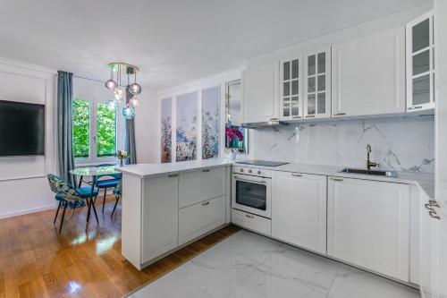 une cuisine blanche avec des armoires blanches et une table dans l'établissement Soft Glam 1-bedroom appt - Lake & Mountain View, à Montreux