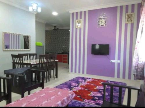 uma sala de jantar com uma mesa e uma parede roxa em Nor Su Homestay em Kampong Alor Gajah
