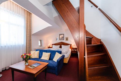ein Hotelzimmer mit einem Bett und einem blauen Sofa in der Unterkunft Aparthotel Seeschlösschen in Zinnowitz