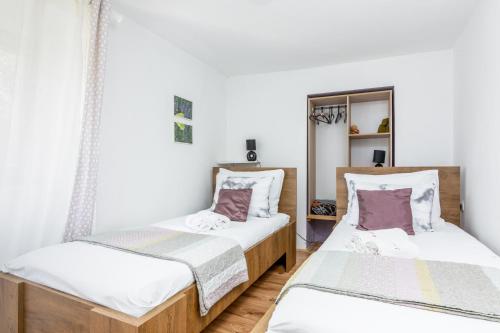 Habitación con 2 camas, paredes blancas y suelo de madera. en Apartments with a parking space Buzet, Central Istria - Sredisnja Istra - 17333, en Buzet