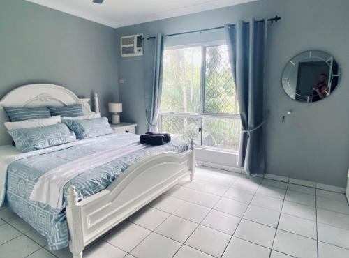 a bedroom with a bed and a mirror and a window at The Palms 3 bedroom comfort in quiet court in Darwin