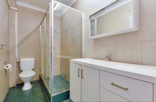 La salle de bains est pourvue de toilettes, d'un lavabo et d'une douche. dans l'établissement The Palms 3 bedroom comfort in quiet court, à Darwin