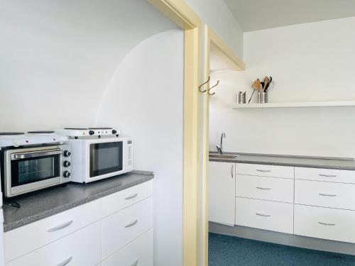 a kitchen with white cabinets and a microwave at aday - Frederikshavn City Center - Charming double room in Frederikshavn
