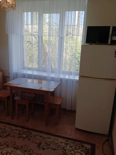 cocina con mesa, nevera y ventanas en Квартира на Абая en Almaty