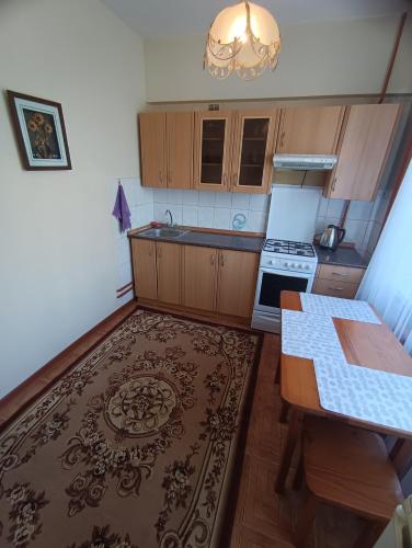 a kitchen with wooden cabinets and a table and a rug at Квартира на Абая in Almaty