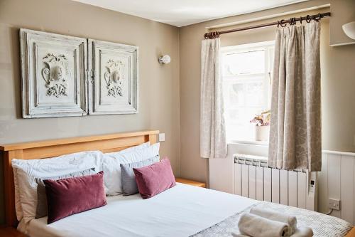 a bedroom with a bed with purple and white pillows at The Bucks Head in Meonstoke