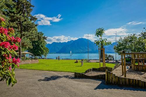 einen Park mit Blick auf das Wasser und die Berge in der Unterkunft Tropical studio with a balcony - Lake View in Montreux