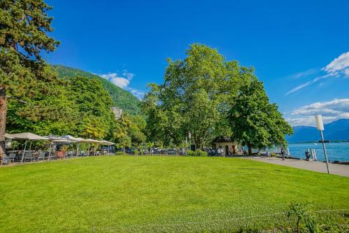 a park with green grass and trees and a body of water at Secret Garden studio – Lakefront in Montreux