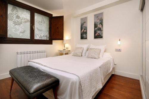 a bedroom with a large white bed and a stool at Laila Home in Barbastro