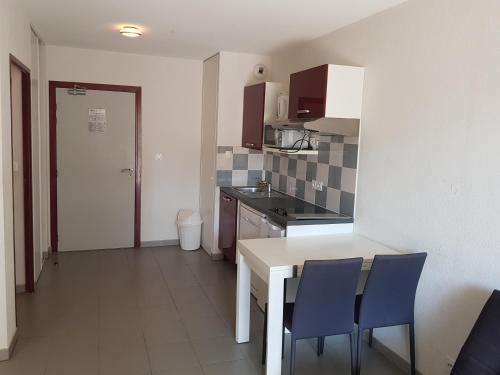 une cuisine avec une table et des chaises dans une pièce dans l'établissement appartement avec terrasse , jardinet et piscine, à Argelès-sur-Mer