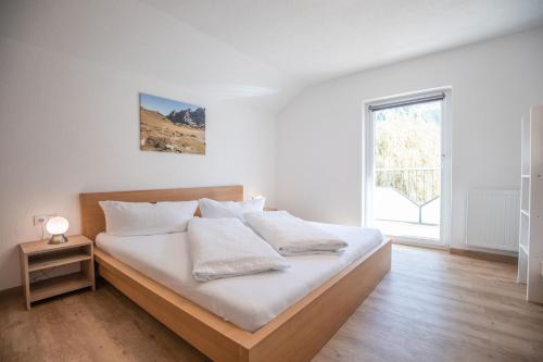 a bedroom with a bed with white sheets and a window at Apart Alp Line in Mils bei Imst
