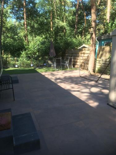 a patio with two chairs and a table and trees at Chalet Hoenderloo in Hoenderloo