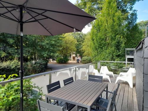 a wooden table and chairs on a deck with an umbrella at Bord de lac - 4/6pers SAUNA - terrasse 20m2 in Vielsalm