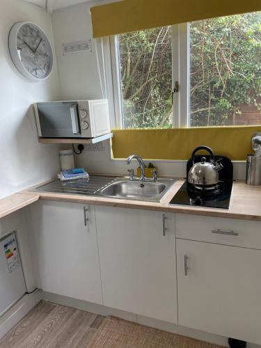 a kitchen with a sink and a clock on the wall at THE LITTLE NEST BEACH sole use accommodation near to bath in Wick