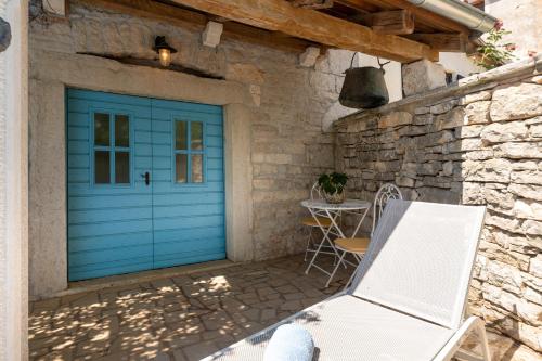 una porta da garage blu con un tavolo e una sedia di Villa Janko a Sveti Lovreč Pazenatički