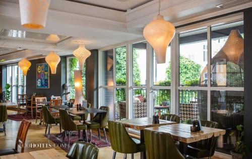 a restaurant with tables and chairs and windows at Carlton 66 Guldsmeden in Copenhagen