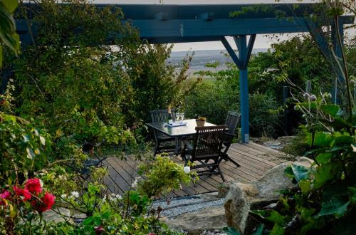 une table et des chaises assises sur une terrasse en bois dans l'établissement Le Charme, à Cernay-lès-Reims