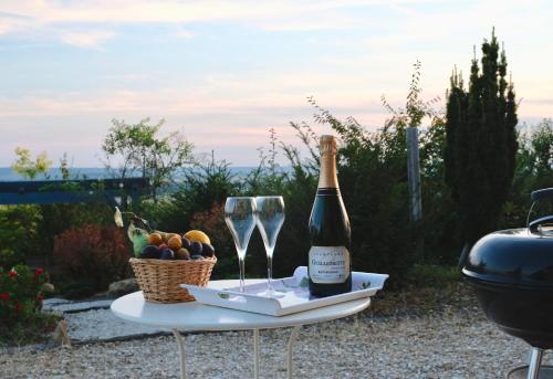 - une bouteille de champagne et une corbeille de fruits sur une table dans l'établissement Le Charme, à Cernay-lès-Reims