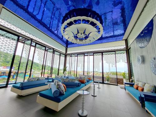 a room with a blue ceiling with couches and windows at The Yama Hotel Phuket - SHA Extra Plus in Kata Beach