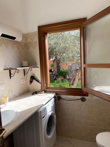baño con lavadora y ventana en Azienda agrituristica contras, en Olbia