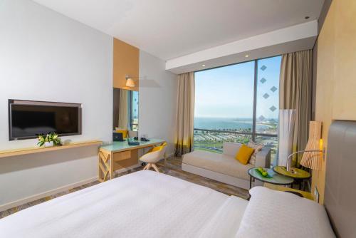 a hotel room with a bed and a couch and a tv at Dana Rayhaan by Rotana in Dammam