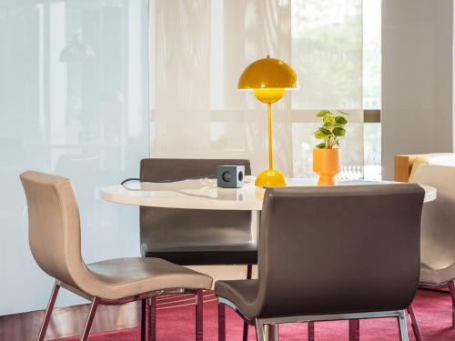 a dining room with a table with chairs and a lamp at Mercure Paris Centre Tour Eiffel in Paris