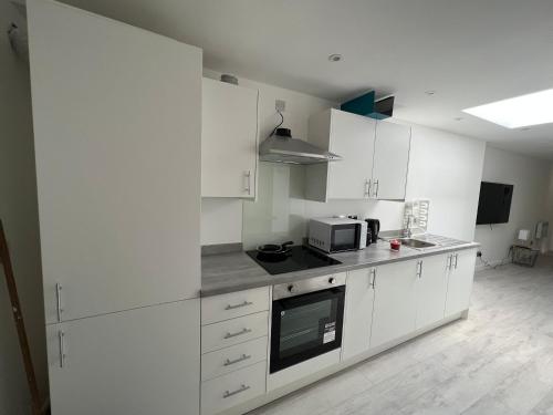 a kitchen with white cabinets and a microwave at Luxury 2 bedroom apartment near the O2 and Canary Wharf in Eltham