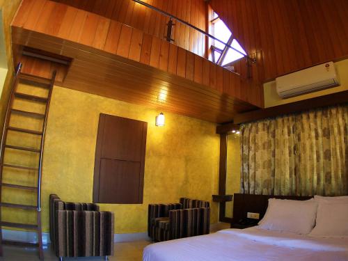 a bedroom with a bed and a ladder and chairs at The Reserve Gorumara in Lataguri