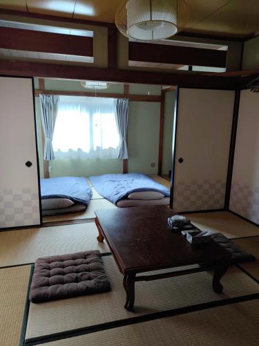 加賀市にあるSIBARIAN Guest Houseのベッド2台、テーブル、鏡が備わる客室です。