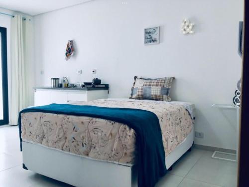 een slaapkamer met een bed met een blauwe deken erop bij Flat Gru in Guarulhos