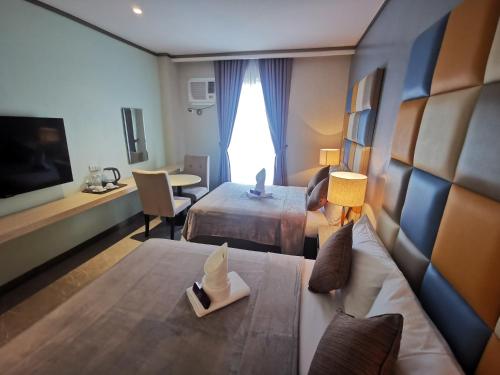 Habitación de hotel con 2 camas y sofá en Yes Hotel Pandi Bulacan, en Pandi