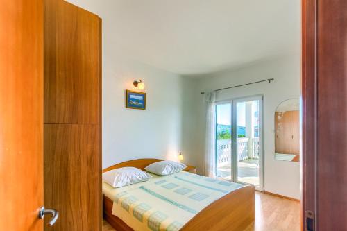 a bedroom with a bed and a door to a balcony at Apartmani Vukičević in Vodice