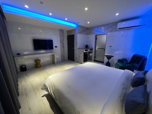 a bedroom with a large white bed and blue lights at MY Motel in Mingjian