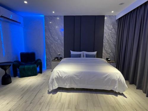 a bedroom with a white bed and a blue wall at MY Motel in Mingjian